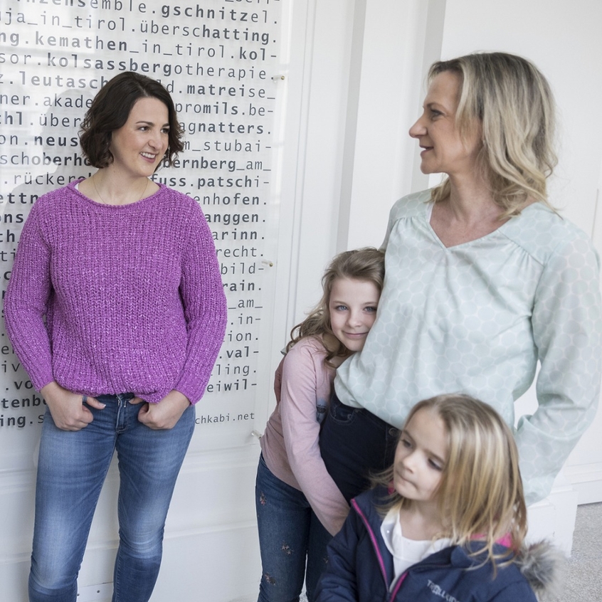 Landesrätin Astrid Mair (li.) spricht mit einer Mutter, die zwei Kinder an der Hand hält.