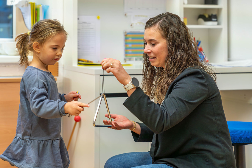 Eine Kindergartenpädagogin mit einem Musikinstrument.