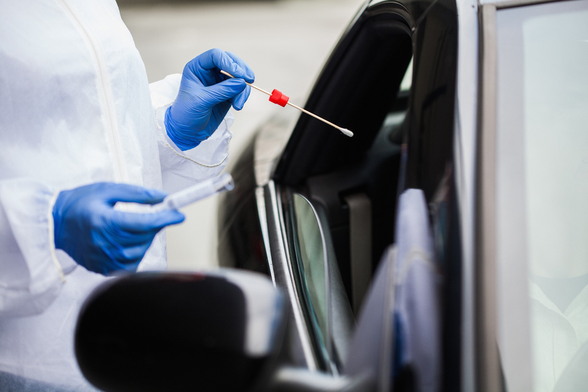 Mediziner mit Teststäbchen bei Auto